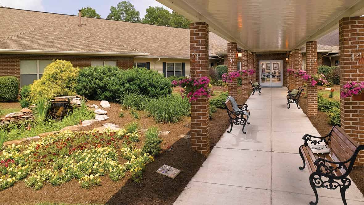 A landscaped garden with a walkway and benches outside a building.