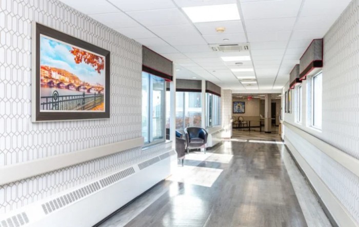A well-lit hospital corridor with artwork and seating.