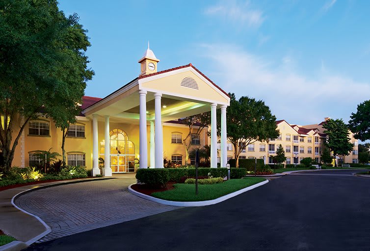 Elegant hotel entrance with large columns and surrounding greenery.
