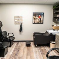 A cozy salon interior with comfortable chairs and a hair wash station.