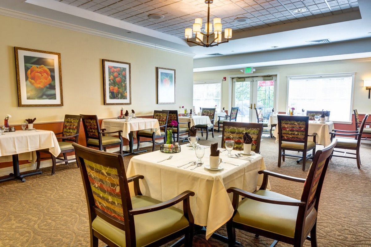 An elegantly set dining area with neatly arranged tables and chairs, featuring pleasant decor and natural lighting.
