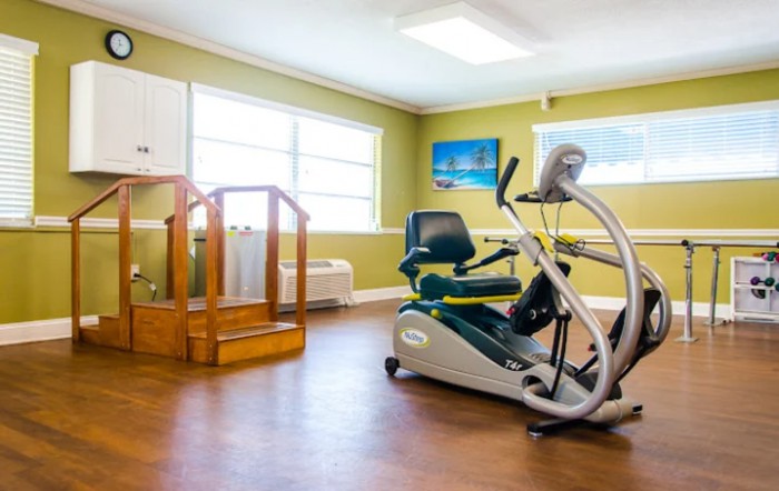 A well-lit rehabilitation room featuring an exercise bike and wooden steps.