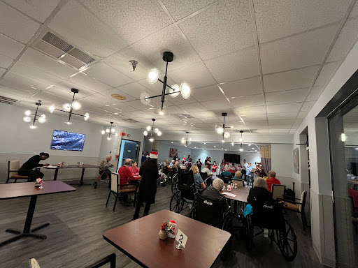 A community gathering space filled with individuals in wheelchairs, enjoying an event under warm lighting.