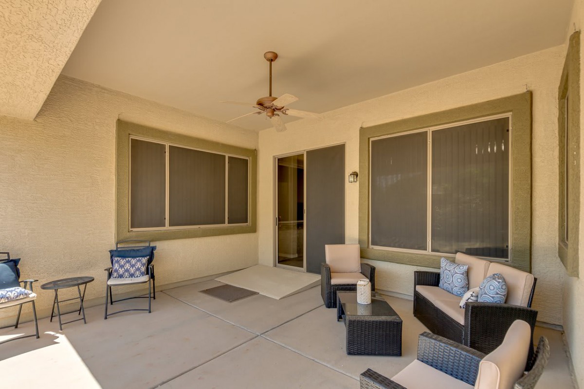 A cozy patio with comfortable outdoor furniture and a ceiling fan.