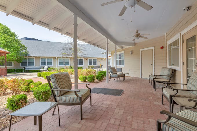 A covered patio with seating and ceiling fans, offering a view of the garden.