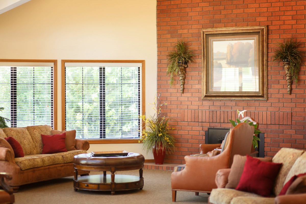 A cozy living room with a brick wall, comfortable seating, and natural light.