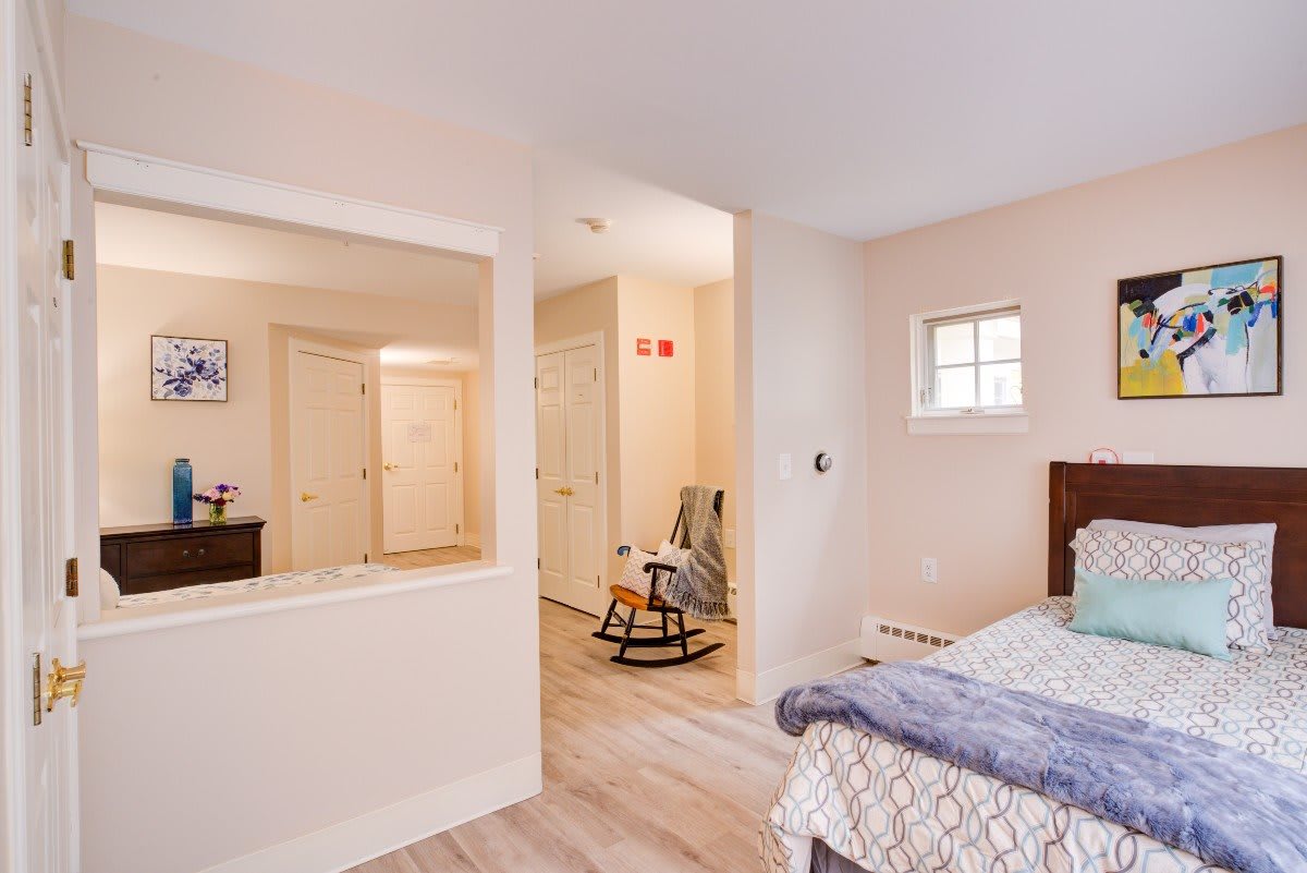 A cozy bedroom featuring a bed, rocking chair, and neutral color palette.