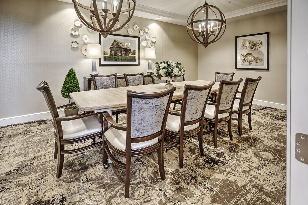 A beautifully decorated dining room with a long table, elegant chairs, and ornate chandeliers.