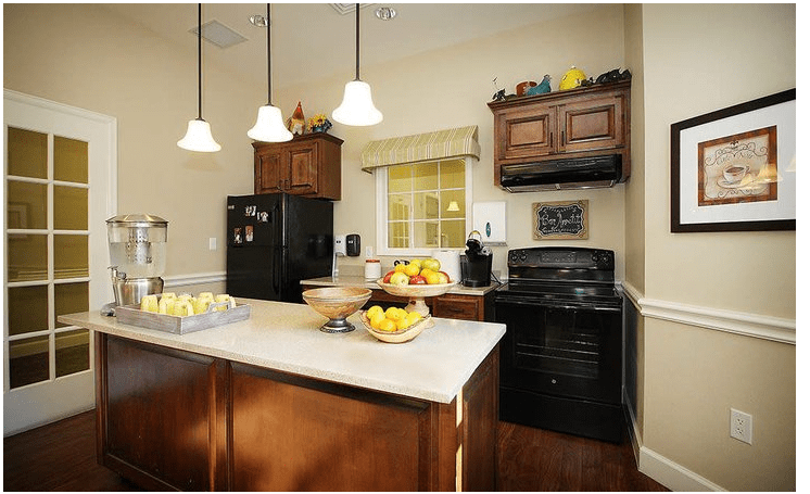 A modern kitchen with wooden cabinets, black appliances, and a central island adorned with fruit bowls.