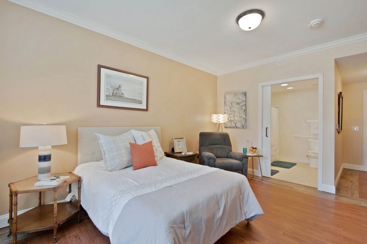 A cozy bedroom with a single bed, armchair, and decorative elements.
