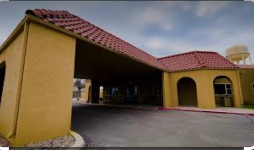 A view of the entrance to a hotel with yellow walls and a red tile roof.