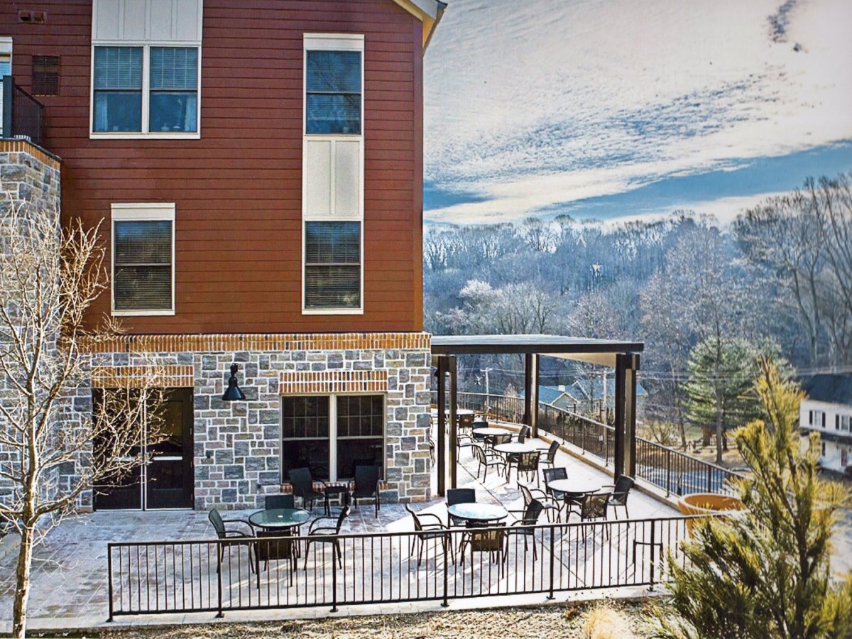 A scenic outdoor patio with tables and chairs overlooking a mountain landscape.