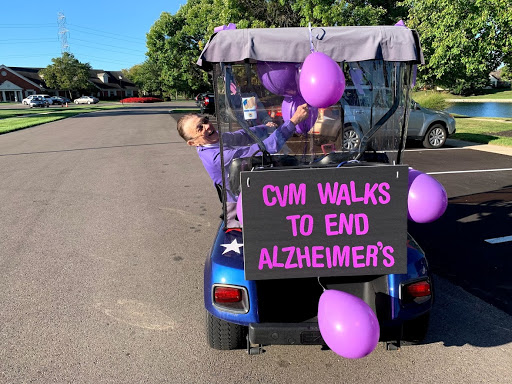 A spirited participant promotes Alzheimer's awareness while riding in a decorated golf cart at a community event.