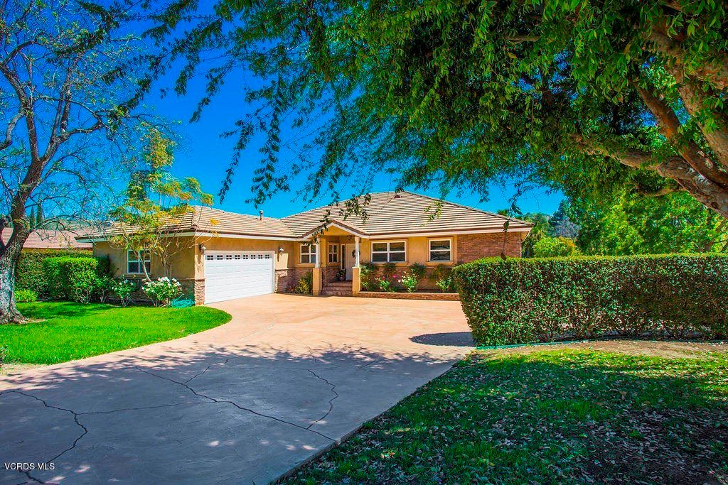 A beautiful suburban house with a driveway and a well-maintained lawn on a sunny day.