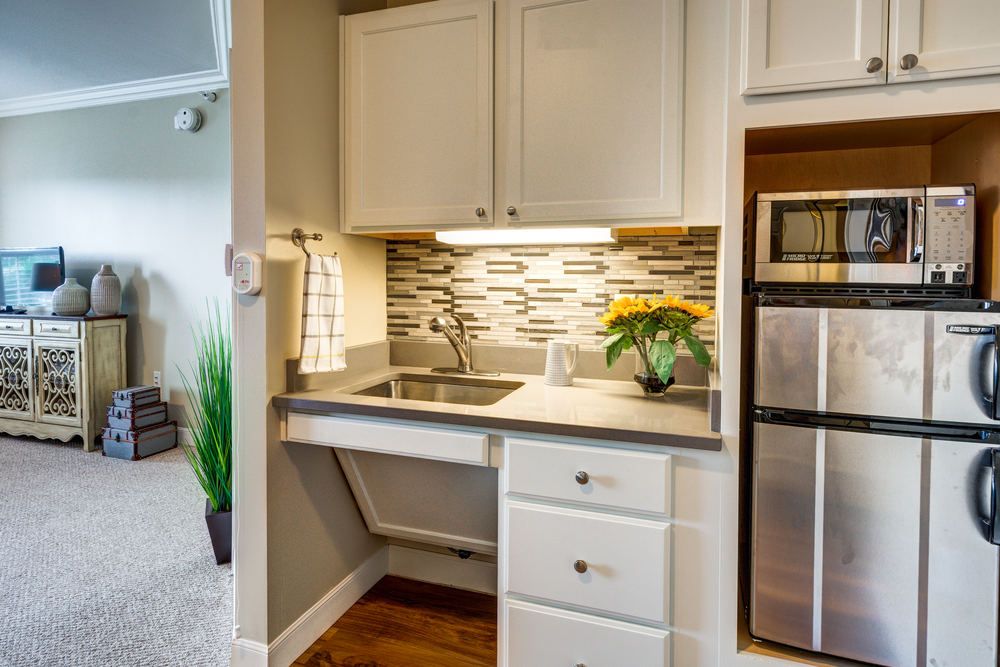 A modern, compact kitchen area featuring a sink, stainless steel appliances, and decorative backsplash tiles.