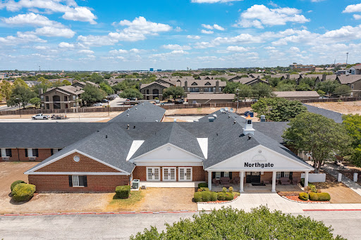 Aerial view of a residential building in a suburban setting, showcasing its architecture against a backdrop of blue skies.