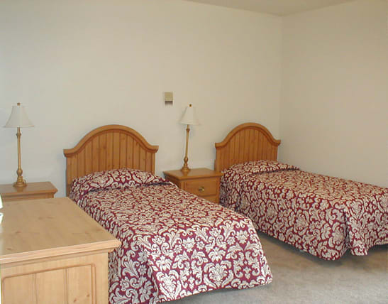 A hotel room with two twin beds featuring matching patterned bedspreads and wooden furniture.
