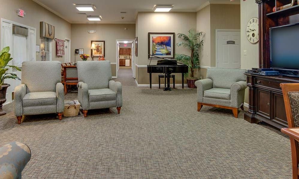 A cozy lobby area featuring comfortable chairs, a piano, and decorative artwork on the walls.