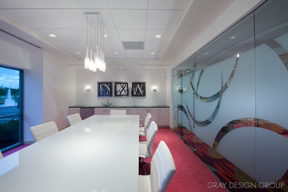 A modern conference room with stylish interior design featuring a large meeting table, glass wall, and contemporary lighting.