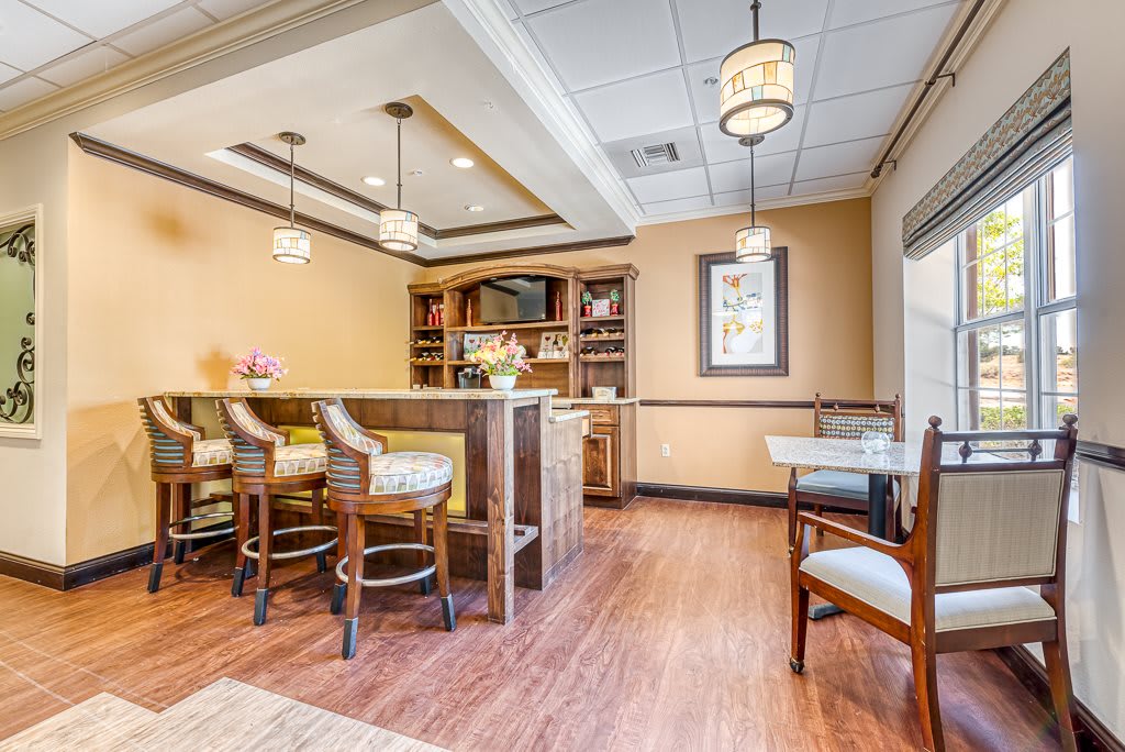 A modern dining area combined with a small library, featuring elegant furniture and pendant lighting.