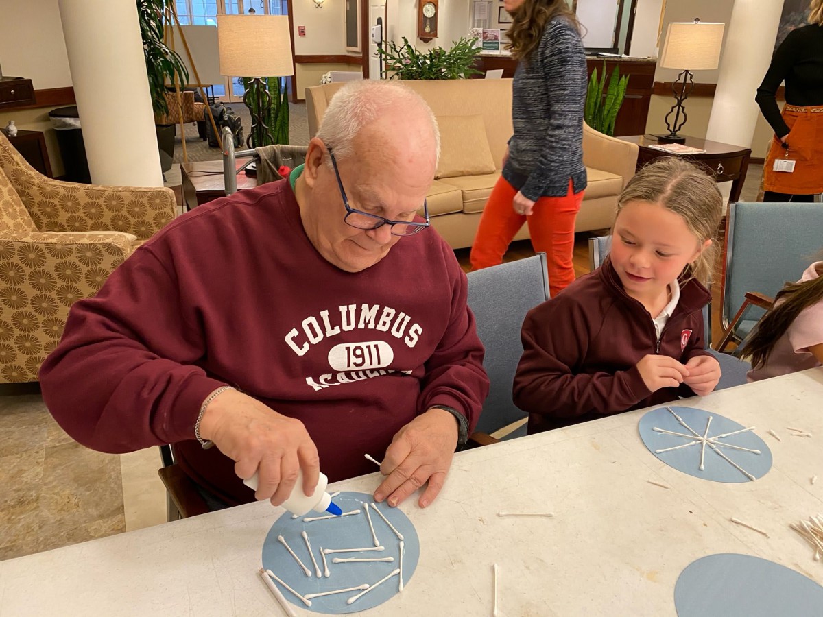 A senior and a child participating in a craft activity together.