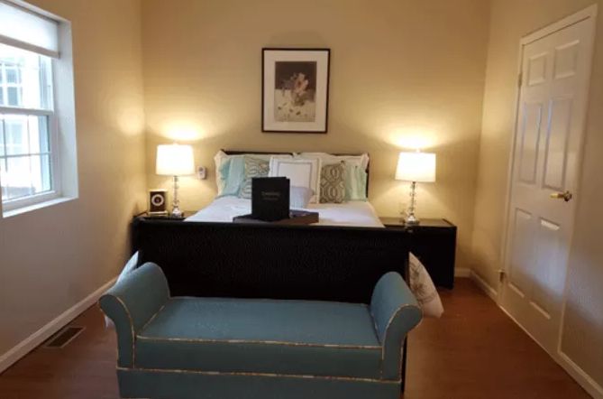 A cozy bedroom with a neatly made bed, flanked by nightstands and lamps, and a bench at the foot of the bed.