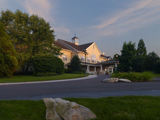 A serene residential building with a welcoming pathway surrounded by lush greenery during sunset.