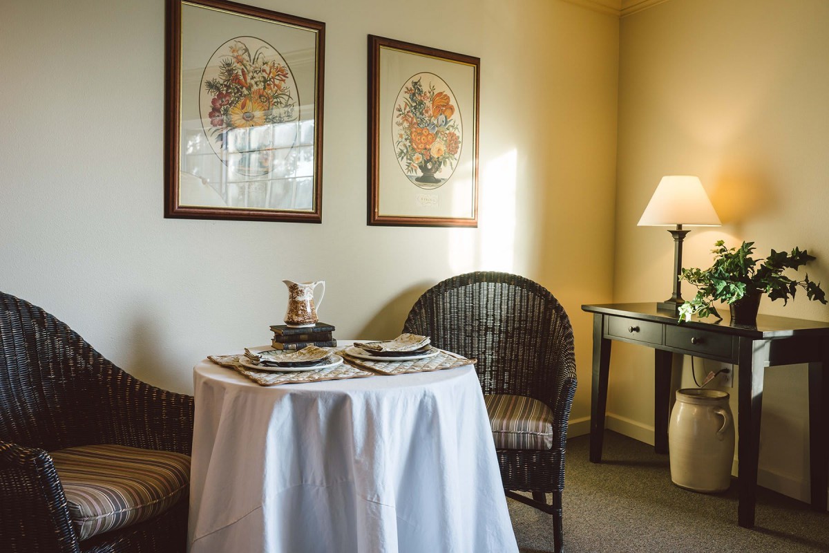 A cozy dining nook with a round table, wicker chairs, and framed artwork.