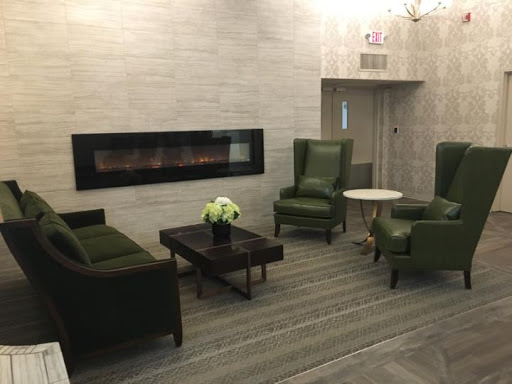 A cozy lobby area featuring green armchairs and a modern fireplace.