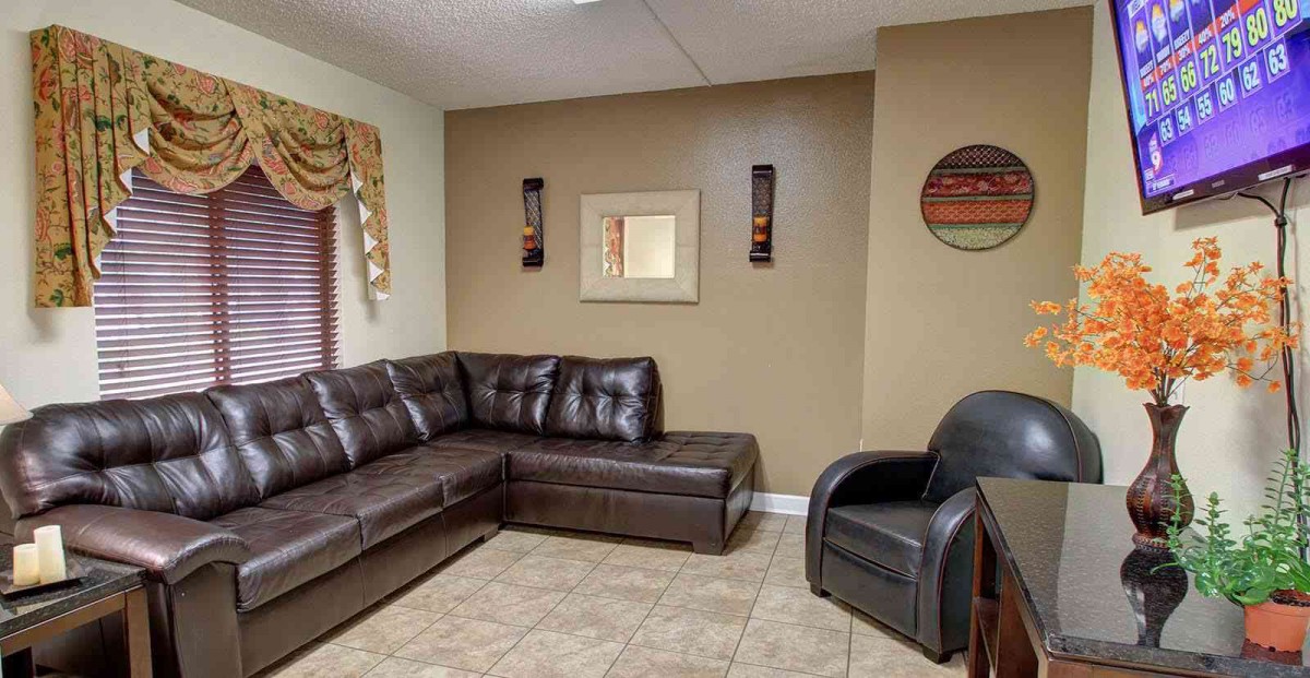 A cozy living room featuring a leather sectional sofa and armchair, with wall decor and tile flooring.