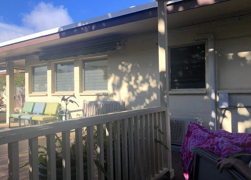 A cozy house exterior with a balcony, featuring a window and some outdoor furniture.