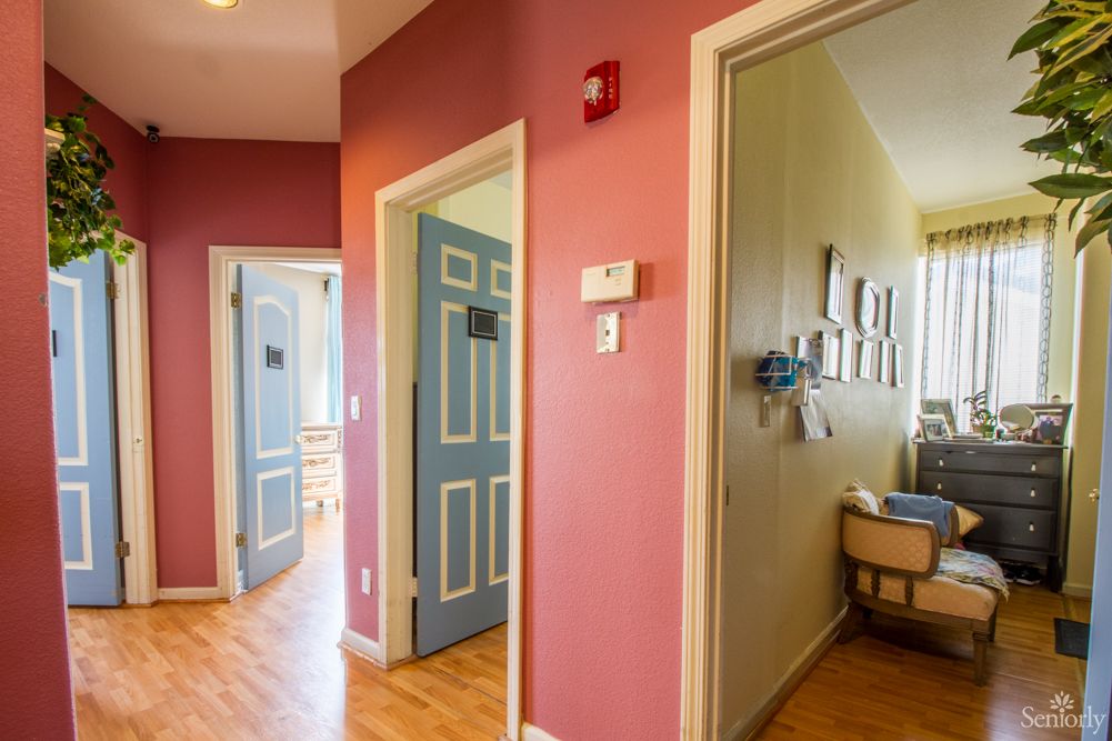 A colorful hallway with multiple doors leading to different rooms, one of which appears to be a nursery.