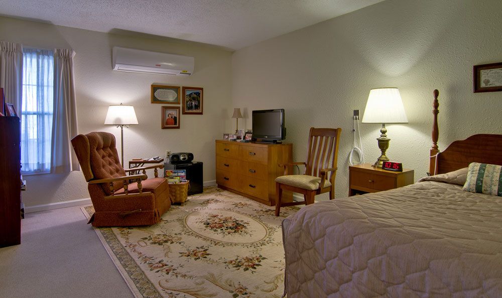 A cozy living room with vintage furniture and decor, featuring a television, lamps, and a patterned rug.