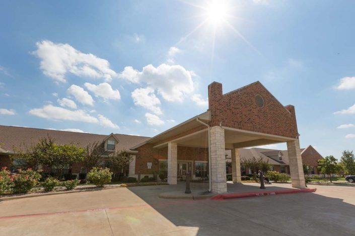A sunny day at the entrance of a large brick building.