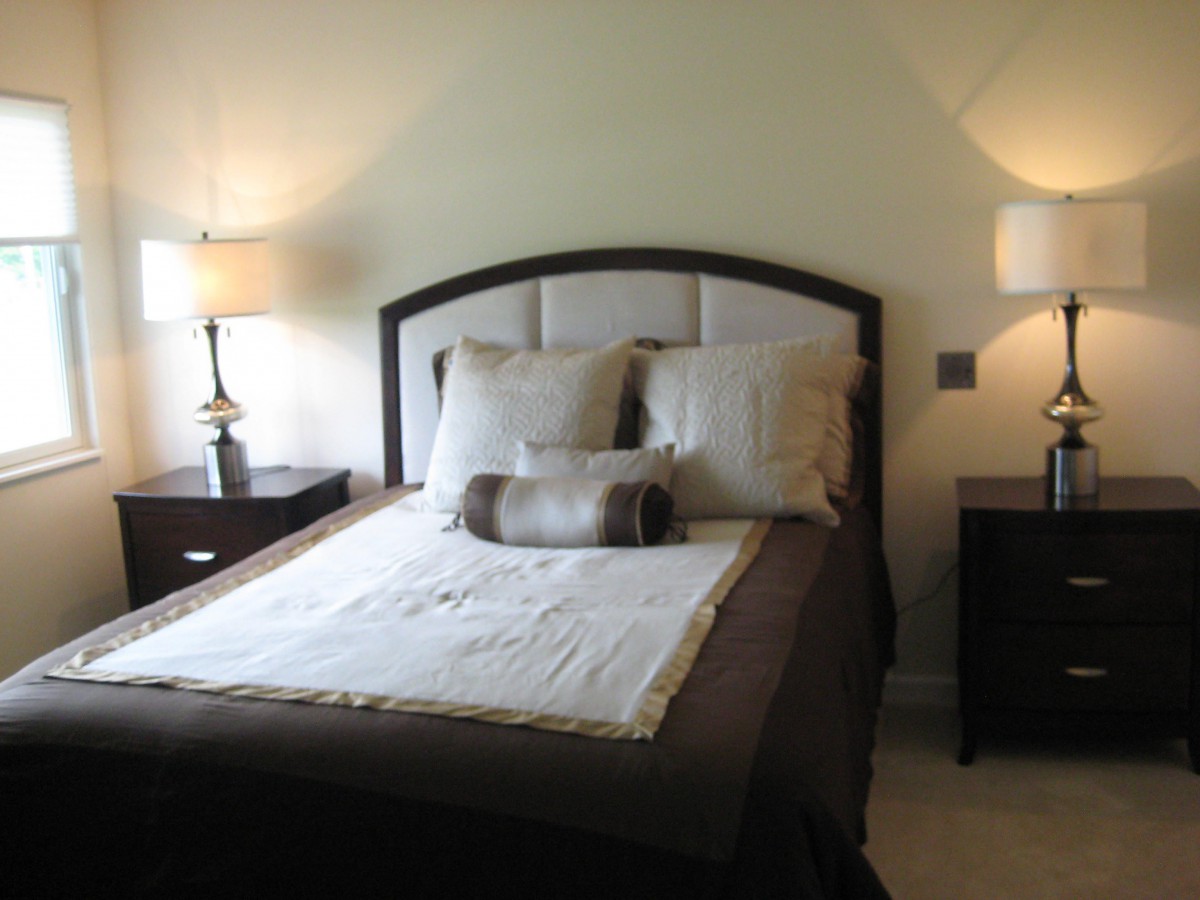 A cozy bedroom with a neatly made bed flanked by stylish lamps on nightstands.