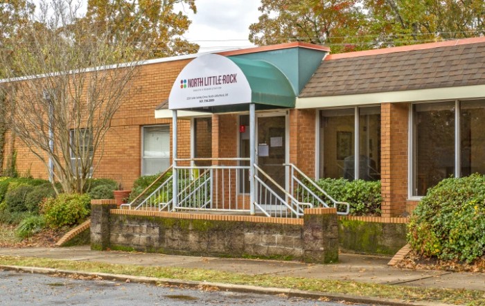 A small brick building with a green and white awning over the entrance.