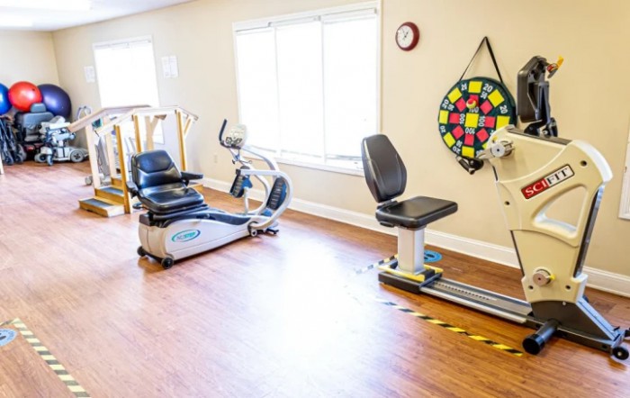 A bright exercise room equipped with stationary bikes and rehabilitation tools.