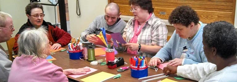 A group of people engaging in a crafting activity with various art supplies on the table.