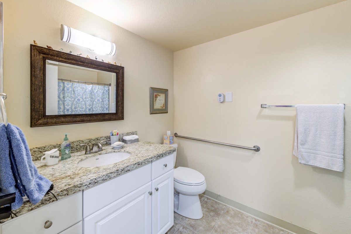 A clean and simple bathroom with a granite countertop and white cabinetry.