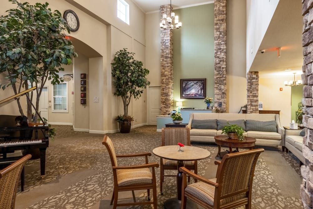 A cozy lounge area with comfortable seating, decorative plants, and a high ceiling.