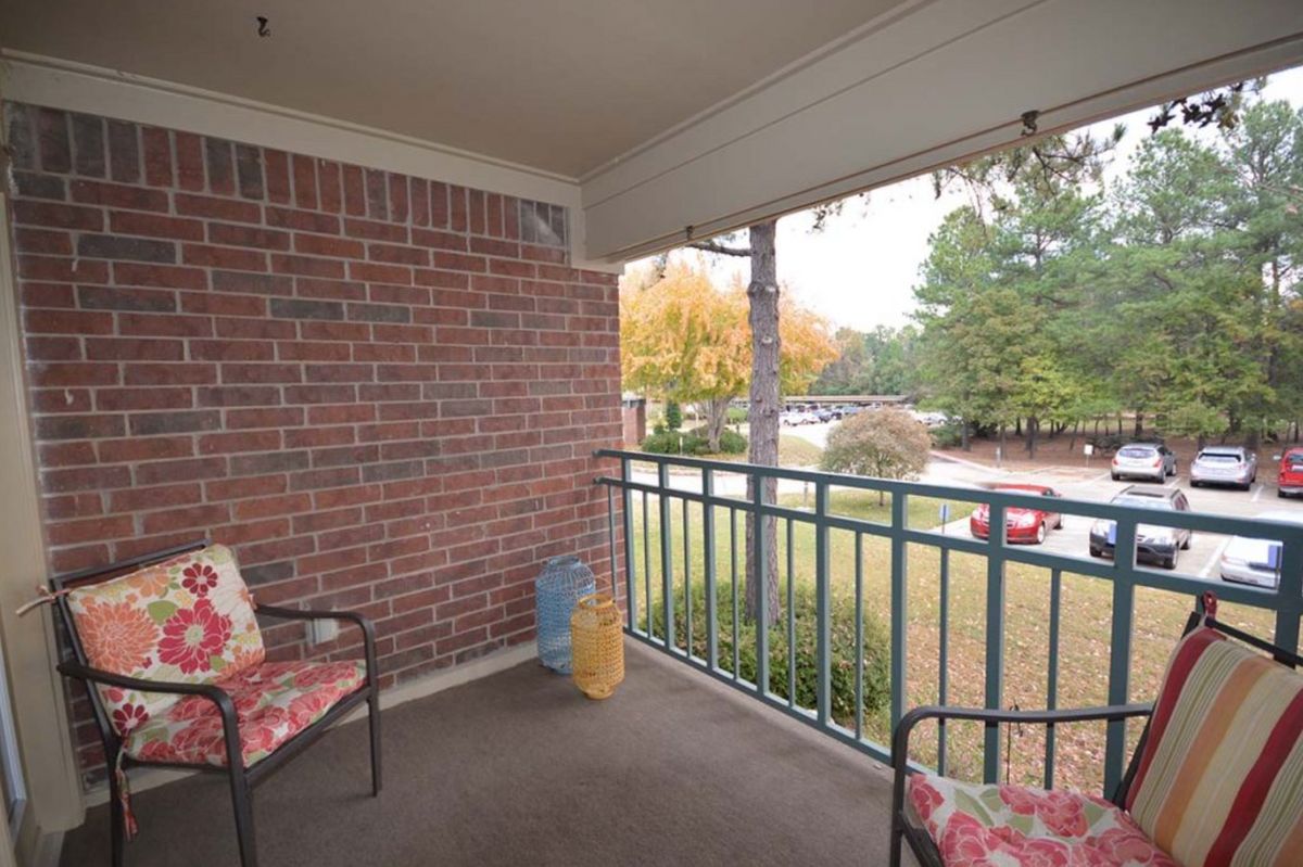 A cozy balcony with chairs overlooking a view of autumn trees.