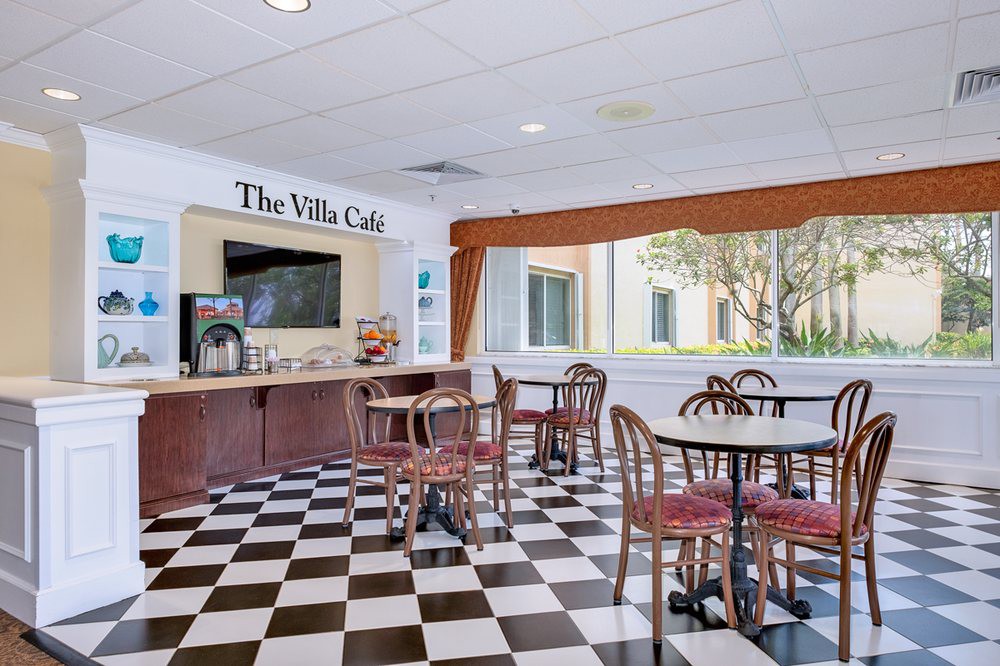 A cozy cafe area with checkered flooring, seating arrangements, and a coffee station.