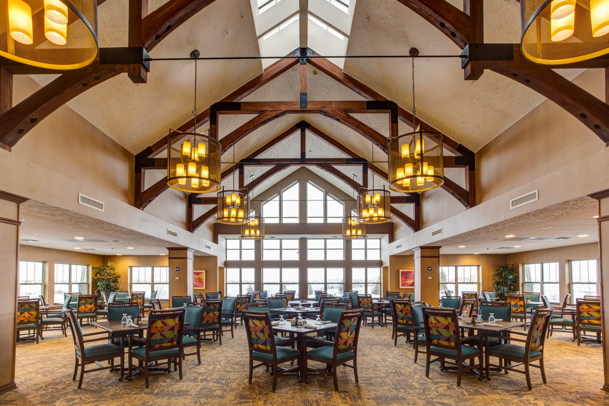 A spacious dining hall with elegant chandeliers and exposed wooden beams.