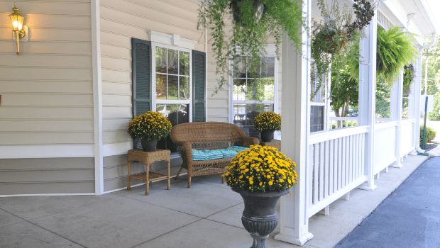 A cozy porch featuring a wooden bench surrounded by vibrant potted flowers and greenery.