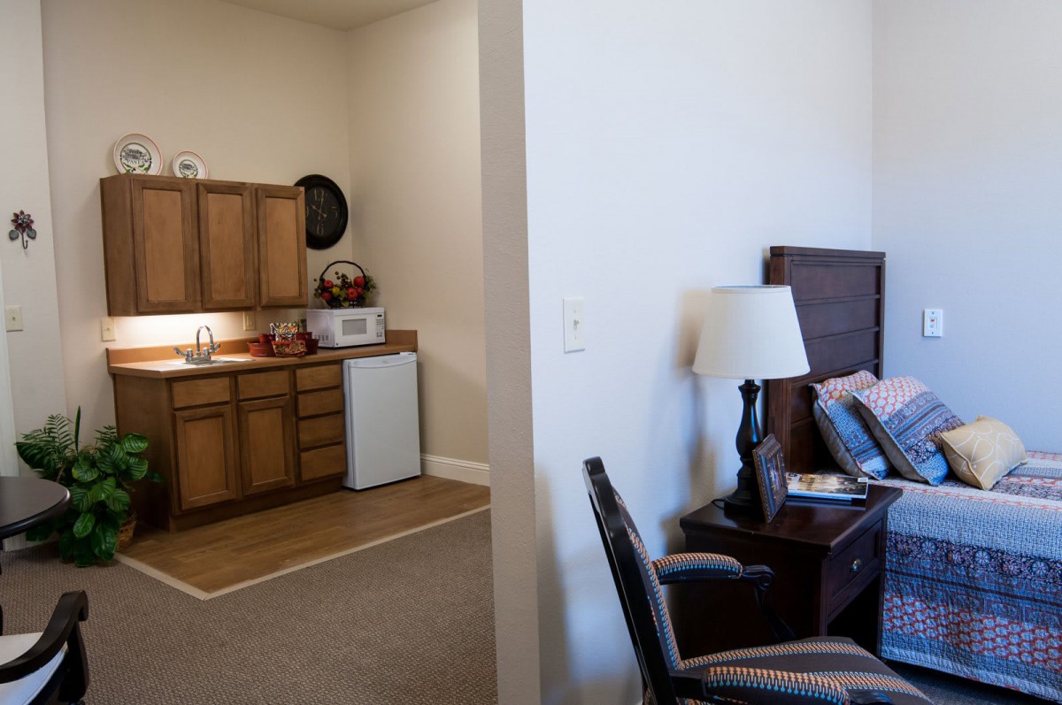 A cozy apartment with a small kitchenette and adjoining bedroom.