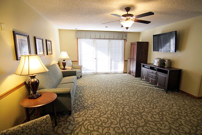 A spacious living room with a sofa, television, and ceiling fan.