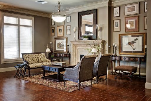A cozy and elegantly designed living room featuring a fireplace, upholstered furniture, and decorative wall art.