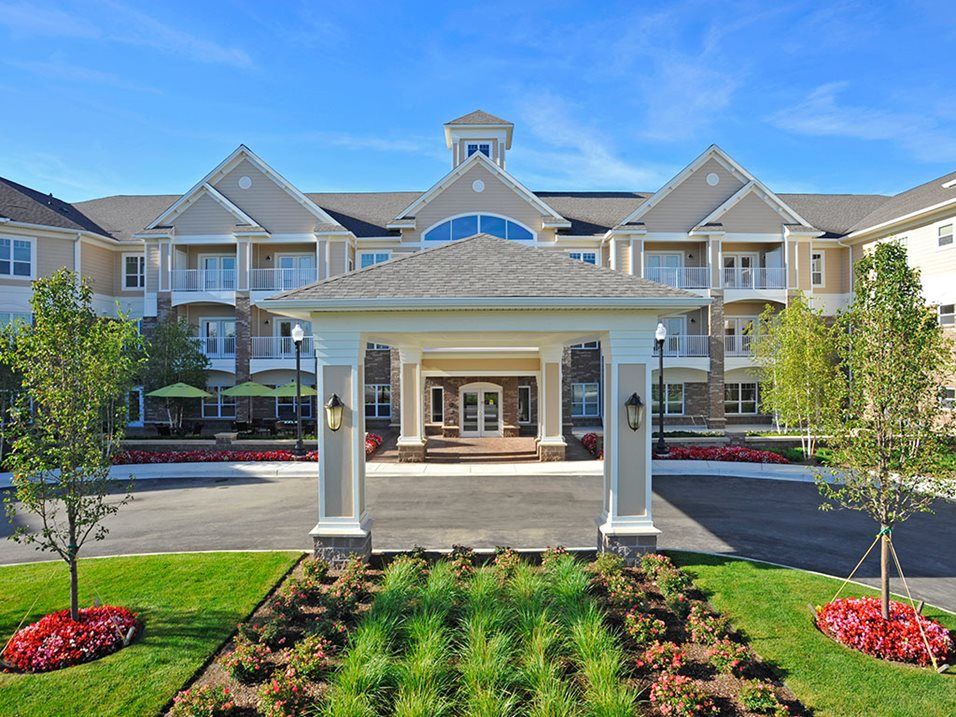 A grand residential building with a landscaped entrance and clear blue sky.