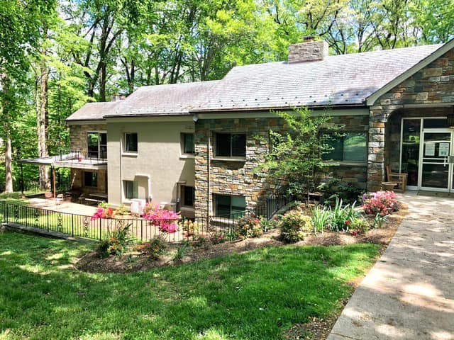 A stone house surrounded by lush greenery and a well-maintained garden.