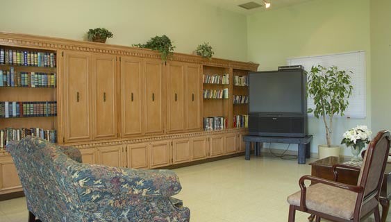 A spacious living room with a large entertainment center and television, featuring wooden cabinetry and a comfortable couch.